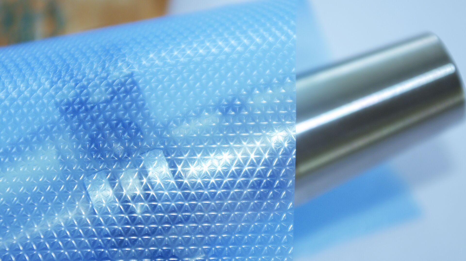 VCI Prägefolie blau – Korrosionsschutzfolie mit geprägter Oberflächenstruktur Nahaufnahme einer blauen BRANOpac VCI Prägefolie mit geprägter Oberflächenstruktur neben einer Metallrolle. Die VCI-Korrosionsschutzfolie schützt Metallteile und Metalloberflächen während Lagerung, Transport und Export vor Rost und Korrosion.