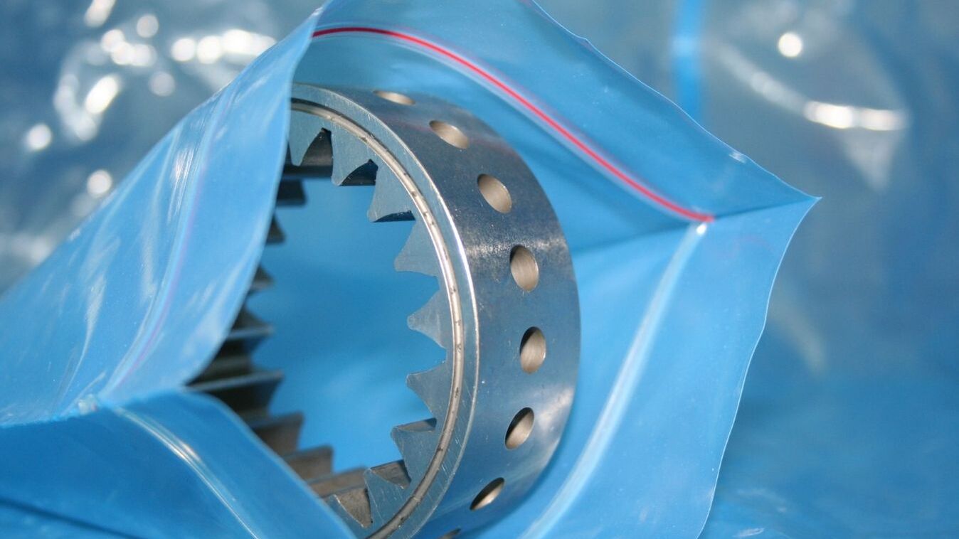 Metallisches Zahnrad bzw. Präzisionsbauteil in blauer VCI-Folie verpackt. Die VCI-Korrosionsschutzfolie schützt Metallteile zuverlässig vor Rost und Korrosion während Lagerung, Transport und Exportverpackung.